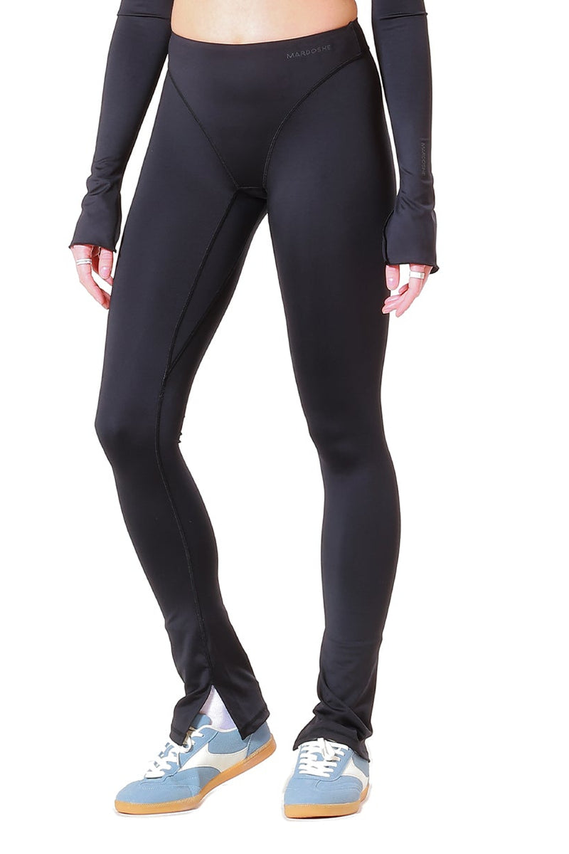 Person wearing a black long-sleeve top and leggings on a white background