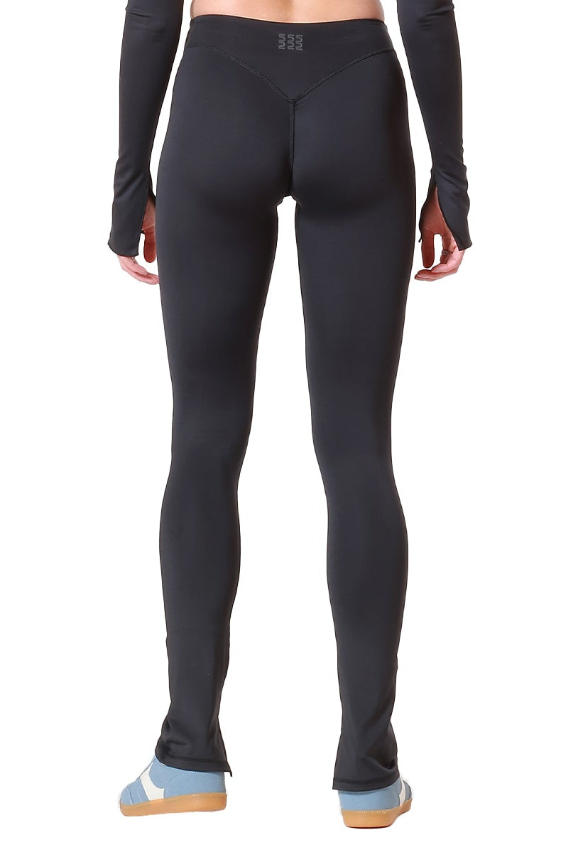 Person wearing a black long-sleeve crop top and leggings on a white background