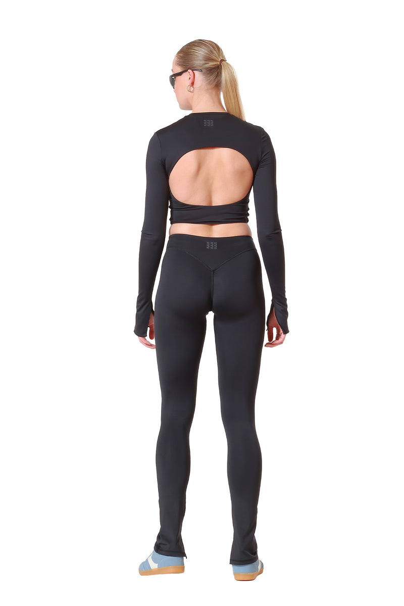 Person wearing a black long-sleeve crop top and leggings on a white background