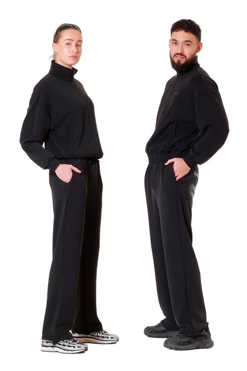 Two people wearing matching black outfits on a white background