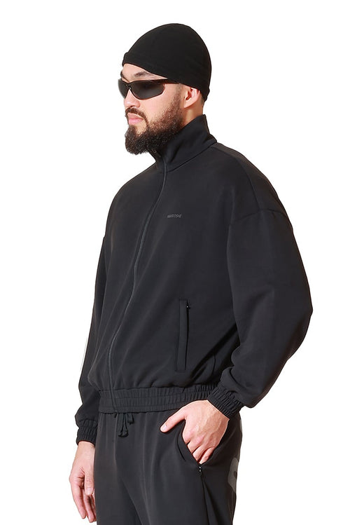 Man wearing a black outfit with sunglasses and a beanie on a white background
